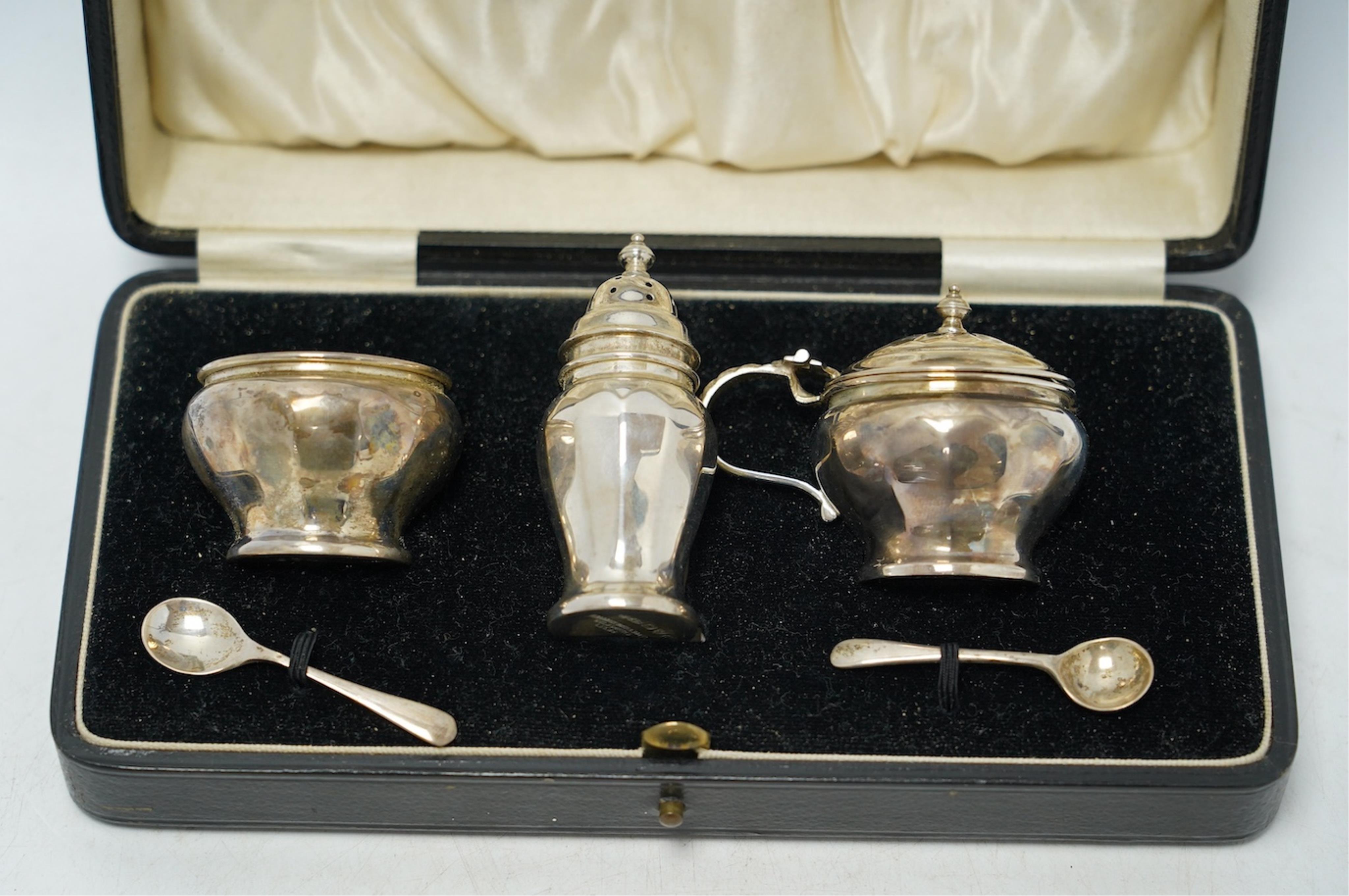 A cased George V silver three piece condiment set, Z. Barraclough & Sons, Chester, 1931, with two associated silver spoons. Condition - fair